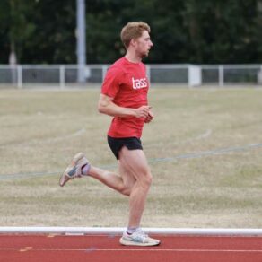 A picture of Tom Wilton, a personal trainer at Team Bath, sprinting around an outdoor athletics track.