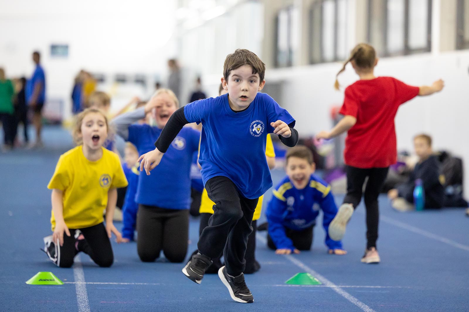 A child is cheered on by his fellow school pupils as he runs on the indoor sprint track at the Team Bath Sports Training Village during a Tribe festival in February 2025. 