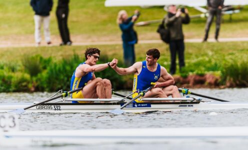 A photo of two University of Bath rowers, sitting in a double scull rowing boat on the river, fist bumping after winning a medal at the BUCS Regatta 2025.