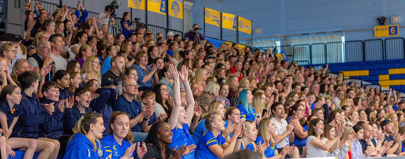 A photo of a packed stand of fans at the Team Bath Arena cheering on Team Bath Netball in their NXT Gen League victory over Loughborough Lightning in May 2025.