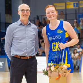 A photo of Most Valuable Player Scarlett Creasey holding a bouquet of flowers that she has just been presented by Stephen Baddeley, Director of Sport at the University of Bath, following Team Bath Netball's NXT Gen League victory over Loughborough Lightning.