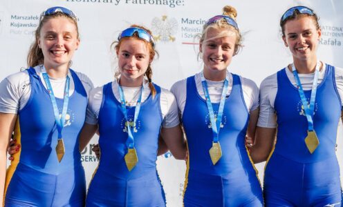 Four rowers, wearing University of Bath rowing club kit, standing arm in arm while wearing gold medals around their necks after winning the women's quadruple sculls title at the 2025 European Universities Rowing Championships