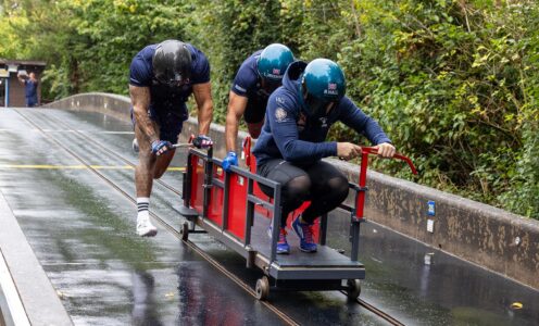 British Bobsleigh pilot Brad Hall jumps into a training cart while two of his team-mates push him down the concrete outdoor push-start track at the University of Bath.