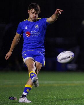 University of Bath rugby player James Linegar kicking a rugby ball off a tee. 
