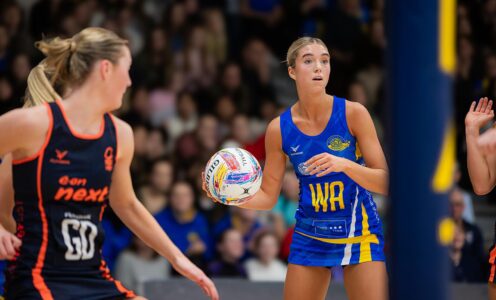 Team Bath Netball player Saskia Lea with ball in hand, watched by a Nottingham Forest defender and a crowd of spectators