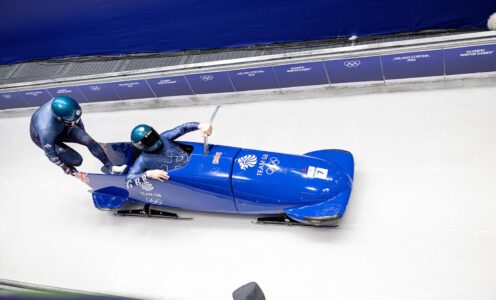 Leon Greenwood and pilot Brad Hall jump into a blue bobsleigh as it slides down an ice track