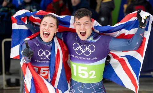 Tabby Stoecker and Matt Weston roar with delight while holding a Union Flag behind them after winning mixed team skeleton gold.