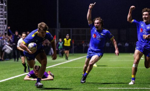 Two players raise their arms in celebration as team-mate Harry Walker prepares to dive across the line for a Bath try