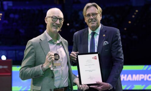 Stephen Baddeley (left) holds a glass award in his right hand as he is presented with a Meritorious Award certificate by BWF Vice President (Europe) Robbert de Kock.