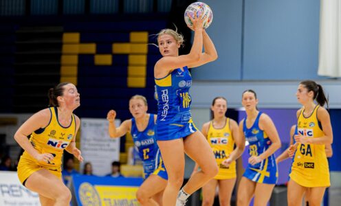Team Bath Netball's Lowri Windsor leaping to catch the ball and turning to look down the court