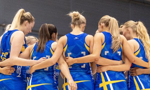 Team Bath Netball players huddle with their arms around each other's backs before a match