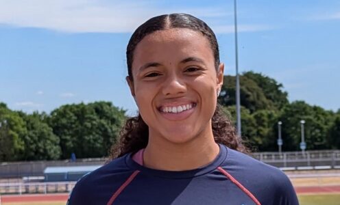 A profile picture of Aleeya Sibbons with the University of Bath outdoor athletics track behind her.