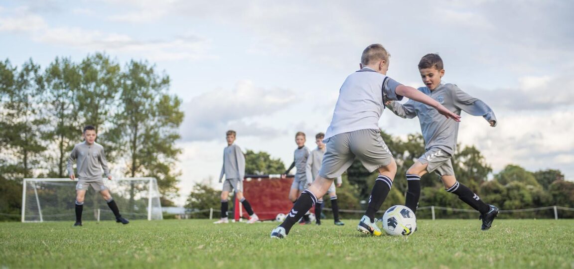 Young boys playing football on a grass pitch