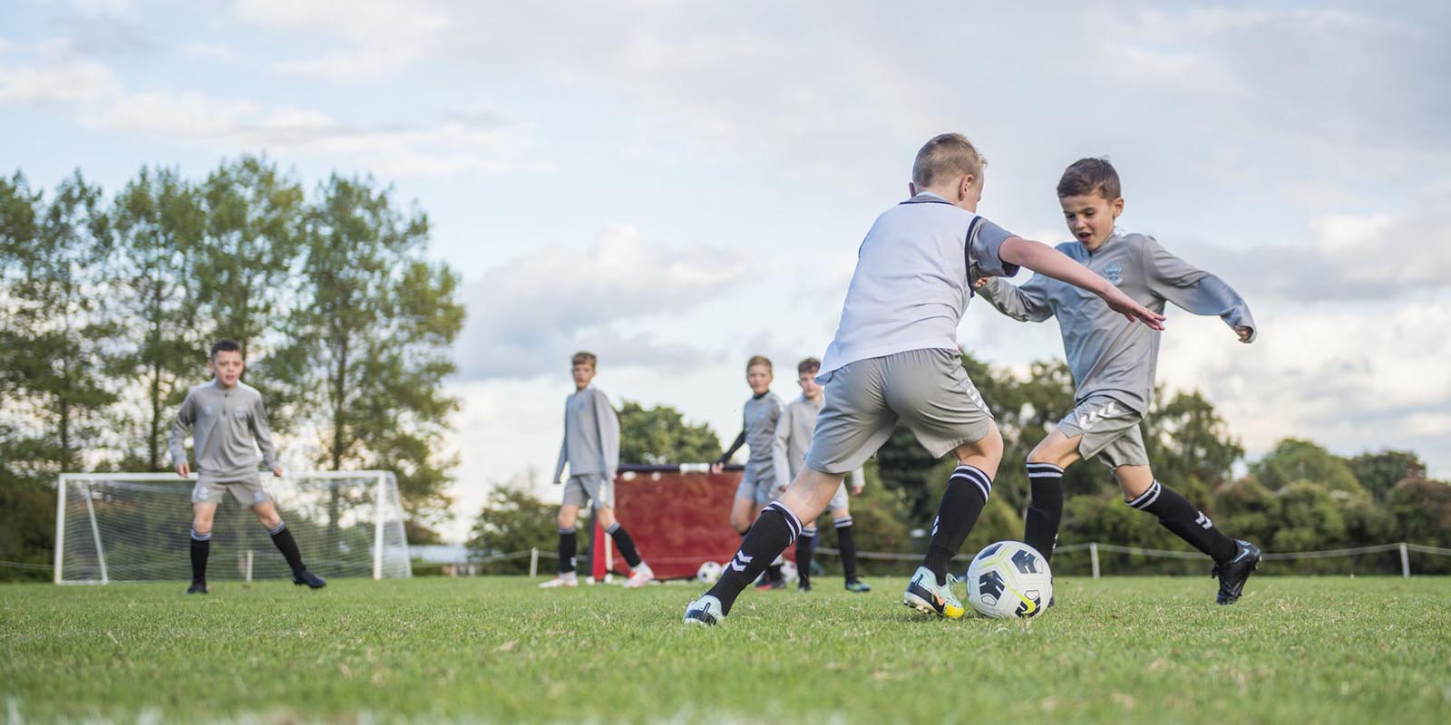 Young boys playing football on a grass pitch