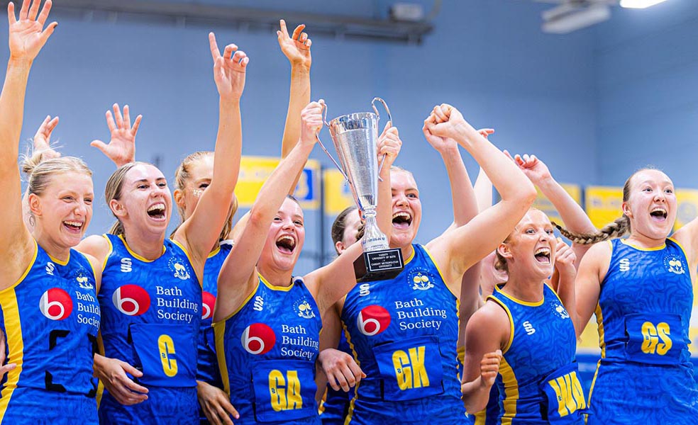 University of Bath student netballers celebrate as they lift a trophy