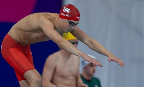 Cam Brooker, wearing a red Team England cap, about to dive into the pool.