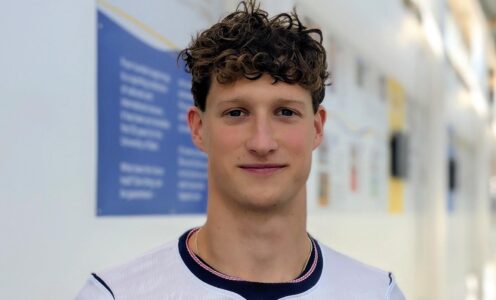 A headshot of swimmer Cam Brooker in front of the University of Bath sporting timeline