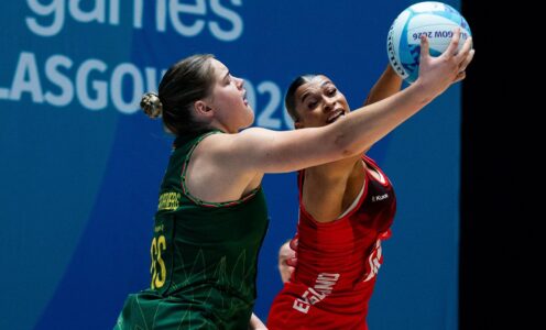 Two netball players with their arms outstretched, tussling for the ball