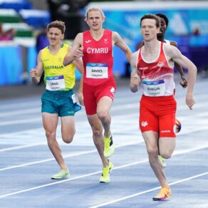 Three athletes running on a blue track