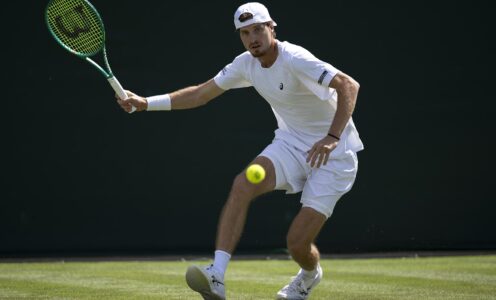 Team Bath Tennis player lines up a shot on a grass court at Wimbledon