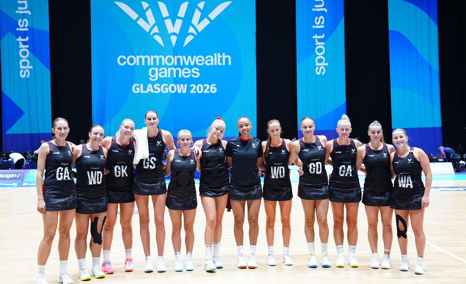 The Wales netball squad line up in front of a Glasgow 2026 Commonwealth Games backdrop