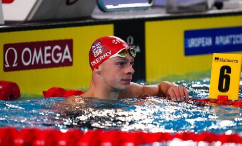 Swimmer Jack Skerry resting against the guide ropes in a swimming pool at the end of a race