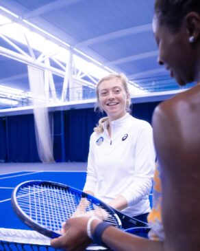 Alicia Barnett speaking to tennis player Esther Adeshina over a net on the indoor courts at Team Bath 