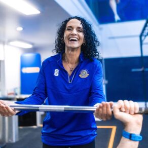 An instrutor in a blue Team Bath top in a gym environment
