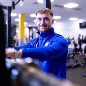 An instructor in a blue Team Bath top in a gym environment