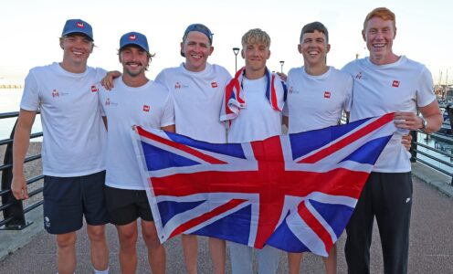 Six men wearing white t-shirts and holding a Union Jack flag