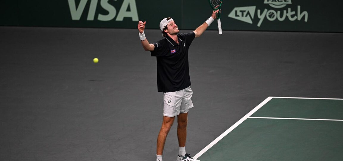 Tennis player Toby Samuel raises his arms in celebration.