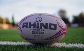 A rugby ball sitting on a green pitch