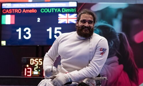 Para fencer Dimitri Coutya smiling in front of a scoreboard showing his 15-13 victory over Amelio Castro