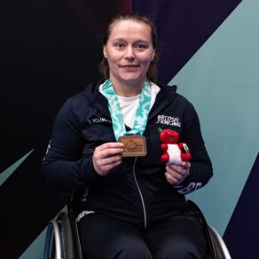 Para fencer Justine Moore with a bronze medal around her neck and holding a red dragon mascot toy